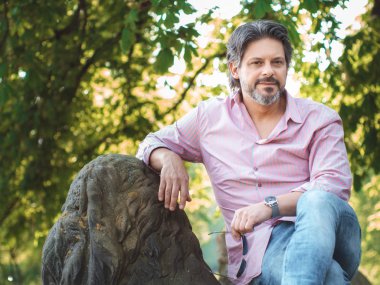 Kendinden emin ve yakışıklı. Oturma ve kameraya, açık seyir yetişkin adam