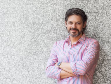 Silah ile gri duvara yaslanmış yetişkin yakışıklı geçti. Muhteşem iş adamı gülme ve kameraya bakıyor. Boşaltmak için metin