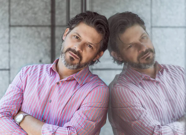 Cam veya ayna yansıması ile çapraz silah kamerayla bakarak ekmek ile sakallı yetişkin adam portresi