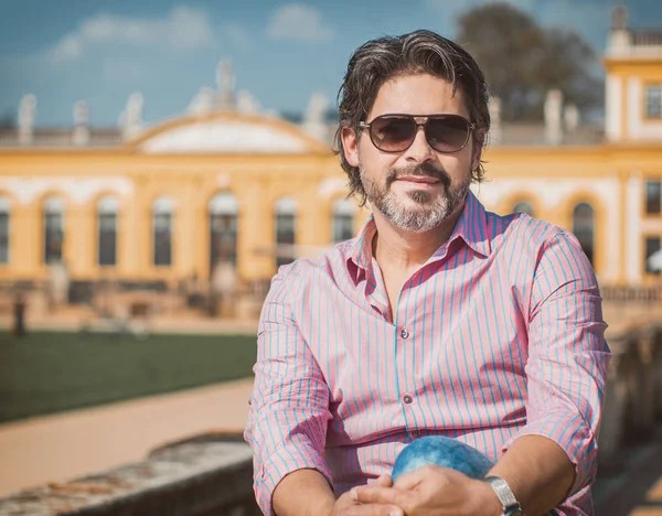 Portre yakışıklı yetişkin adam giyen güneş gözlüğü ve pembe - kırmızı t-shirt, açık havada yaz 