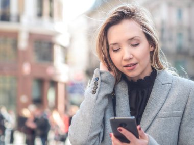 Açık havada bir smartphone kullanarak sokakta yürüyen kadın 