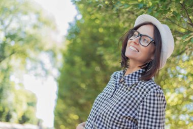 Yan ya da bulanık doğa arka plan önünde bir şey arayan genç kadın gülüyor. Orman içinde yakın çekim Kadın