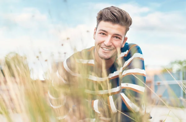 Красивий Хлопець Показує Білі Зуби Посміхаючись Камері Через Розмиту Траву — стокове фото