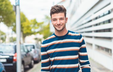 Modern saç stili olan yakışıklı genç adam sokakta yürüyor, dışarıda güzel bir adam var. Yarım uzunluk