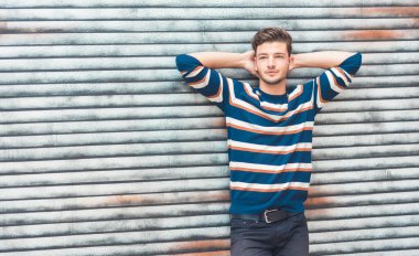 Seksi genç adam poz veriyor, yakışıklı adam renkli bir kazak giyiyor. Boşluğu kopyala