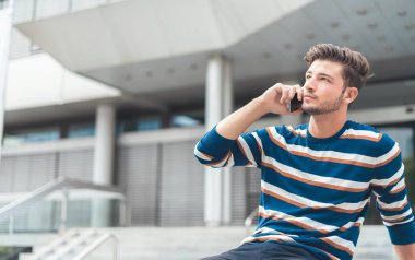 Akıllı telefondan konuşan genç adam. İletişim konsepti, açık hava.