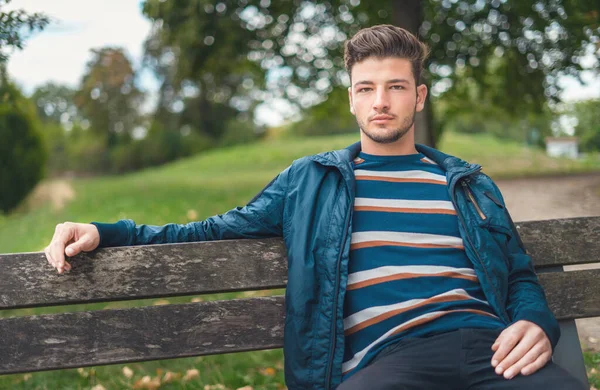 腰を上げて若い男がベンチの公園に座っている 男リラックス屋外 — ストック写真