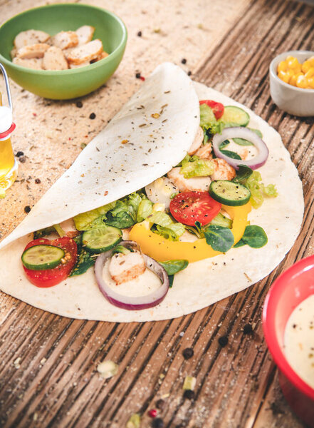 Homemade tortillas wraps with chicken and vegetables on wooden table