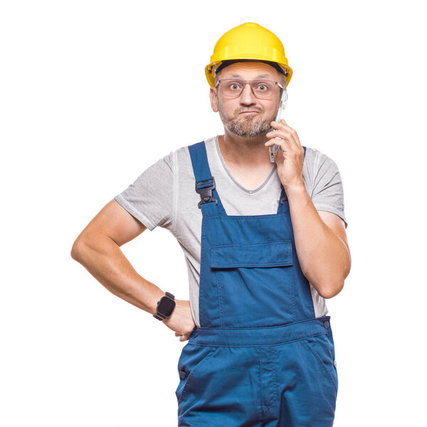 Нервный рабочий, показывающий ее мобильный телефон, изолированный на белом фоне. Разъяренный ремонтник показывает смартфон. Снимок студии