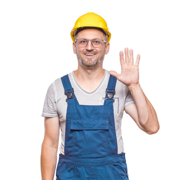 Я клянусь. Строитель средних лет делает ругательный жест и держит руку на груди, глядя на камеру, изолированную на белом фоне. Присягу на верность. Ремесленник против белой стены