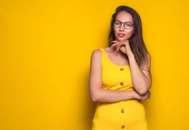 Pretty woman posing while looking to camera, isolated on yellow background. Copy space. Pretty girl. Studio shot