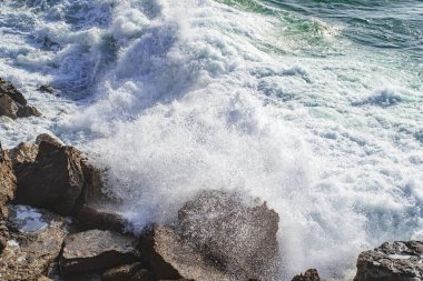 Yakın tepe noktası kıyıya yakın taşlara karşı akan su. Köpüklü yüzeyi olan deniz suyu. Atlantik Okyanusunun Gücü