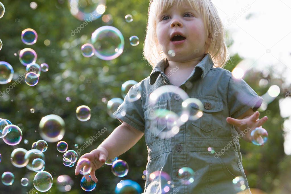 Young Girl In Garden Chasing Bubbles