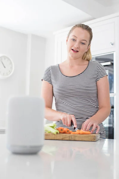 Woman Preparing Food At Home Asking Digital Assistant Question