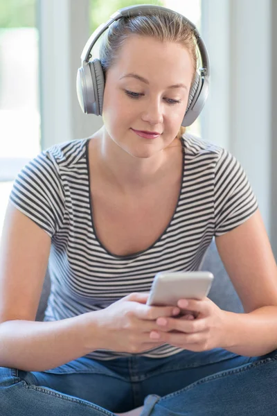 Woman At Home Streams Music From Mobile Phone To Wireless Headphones