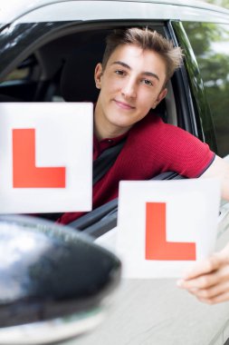 Genç çocuk öğrenen levhaları tutan sürüş sınavı geçtikten portresi