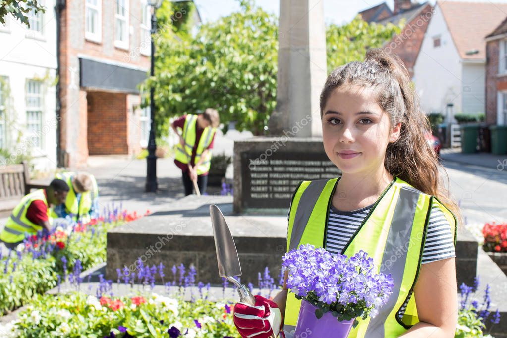 Group Of Helpful Teenagers Planting And Tidying Communal Flower Beds