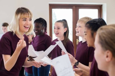 Children In School Choir Being Encouraged By Teacher clipart