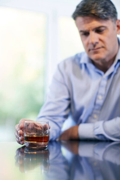 Unhappy Mature Man With Alchol Problem Holding Glass Of Whiskey At Home