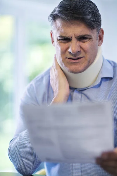 Mature Man Reading Letter After Receiving Neck Injury