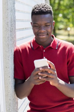 Genç çocuk açık havada cep telefonundan kısa mesaj göndermek