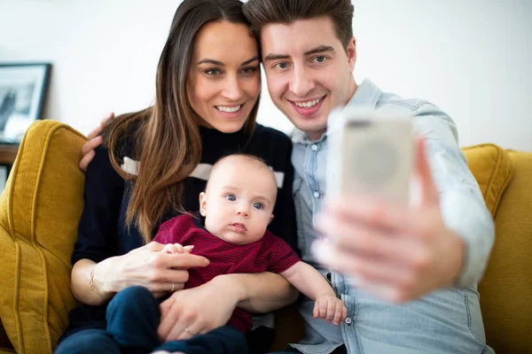 Family Sitting On Sofa At Home Posing For Selfie On Mobile Phone