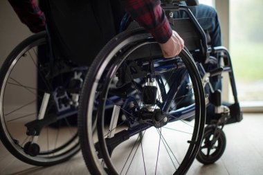 Evde pencere tarafından tekerlekli sandalyede oturan adam, yakın çekim