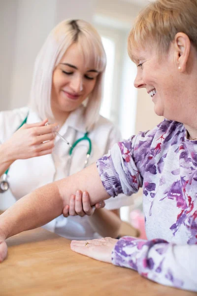 Enfermera dando inyección de mujer mayor en brazo con jeringa —  Fotos de Stock