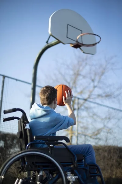 Teenager im Rollstuhl spielt Basketballkorb — Stockfoto