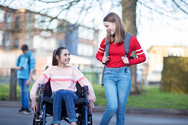 Hig çıkarken arkadaşıyla konuşurken tekerlekli sandalyede genç kız — Stok fotoğraf
