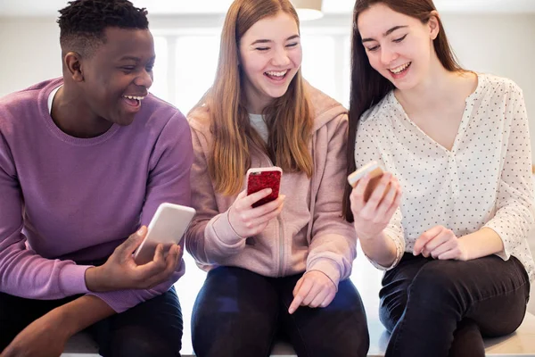 Three Teenage Friends Laughing As They Share Content On Mobile P — Stock Photo, Image