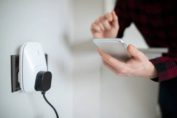 Man Controling Smart Plug використовуючи додаток на мобільному телефоні — стокове фото