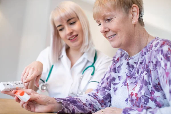 Vrouwelijke verpleegkundige medicatie met Senior vrouw patiënt bespreken — Stockfoto