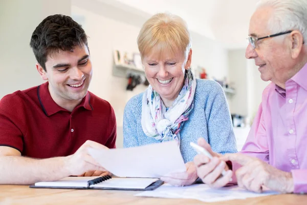 Young Man Helping Senior Couple With Financial Paperwork At Home — Stock Photo, Image