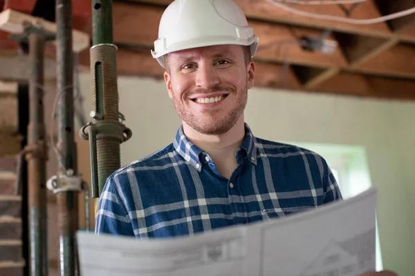 Retrato do arquiteto dentro da casa a ser renovado estudando plano — Fotografia de Stock