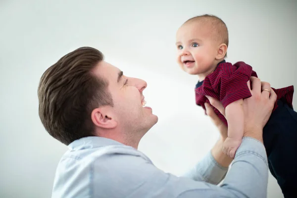 Padre levantando sonriente bebé hijo en el aire en casa mientras juegan Ga — Foto de Stock