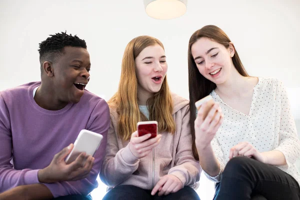 Three Teenage Friends Laughing As They Share Content On Mobile P — Stock Photo, Image