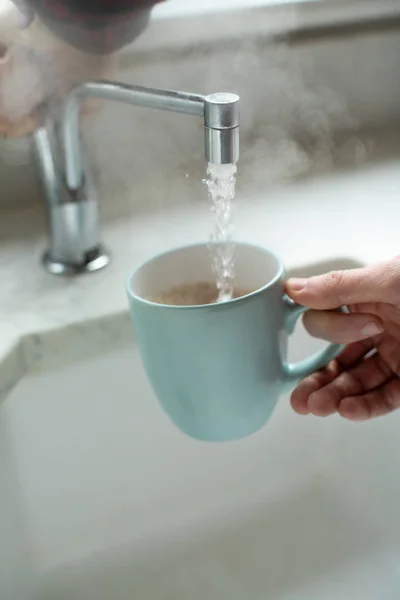 沸騰した水道から熱い飲み物を作る男のクローズアップ — ストック写真