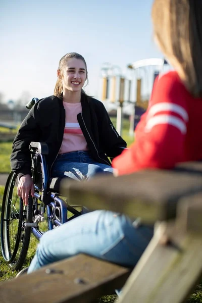 Teenager im Rollstuhl unterhält sich im Park mit Freundin — Stockfoto