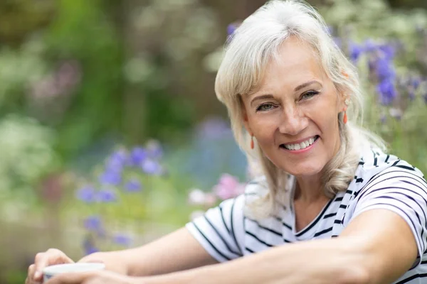 Porträt einer Seniorin, die es sich im heimischen Garten gemütlich macht — Stockfoto