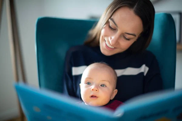 Bebé hijo sentado en madres vuelta lectura historia libro juntos — Foto de Stock