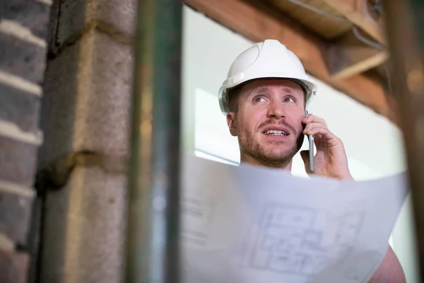 Arquitecto dentro de la casa está siendo renovado estudiando planes de conversación — Foto de Stock