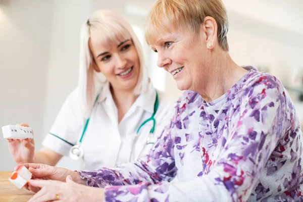 Vrouwelijke verpleegkundige medicatie met Senior vrouw patiënt bespreken — Stockfoto