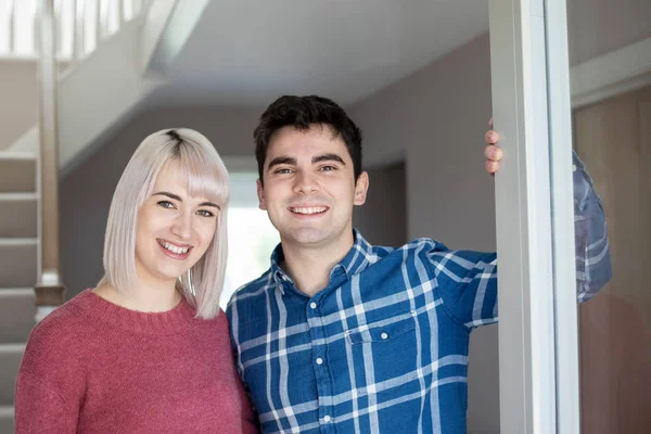 Retrato de casal jovem sorridente que abre a porta dianteira da nova casa — Fotografia de Stock