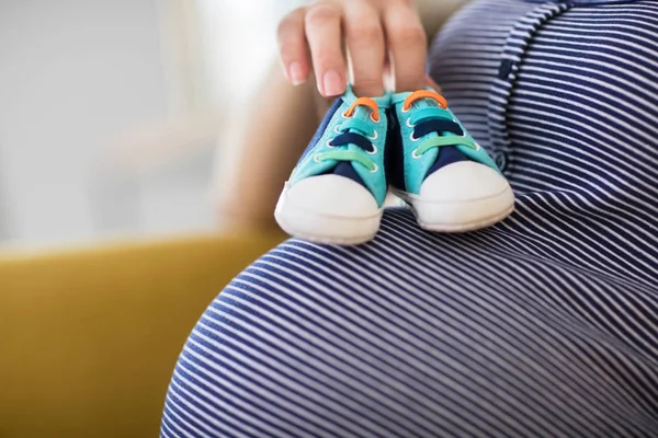 Gros plan de la femme enceinte assise sur le canapé à la maison tenant bébé — Photo