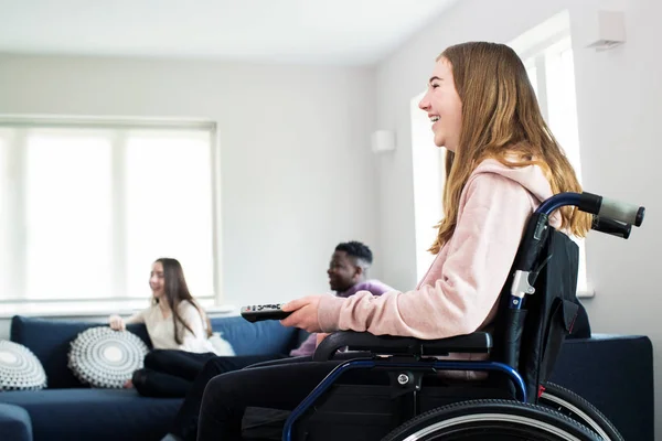 Teenagermädchen im Rollstuhl mit Freinds vor dem Fernseher — Stockfoto