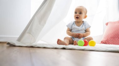 Çadırda oturan ve evde oyuncaklarla oynayan erkek bebek