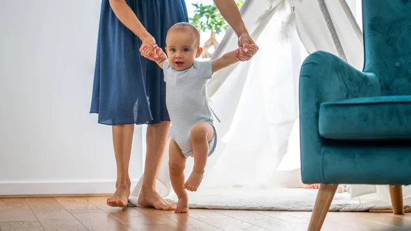 Mère aidant bébé fils à faire les premiers pas à la maison — Photo