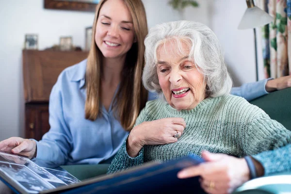 Mormor tittar på fotoalbum med vuxna barnbarn — Stockfoto