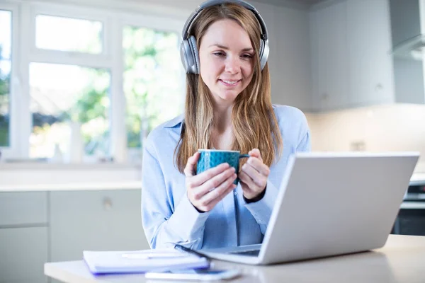 Mujer estudiando en casa usando el ordenador portátil y el uso de auriculares — Foto de Stock